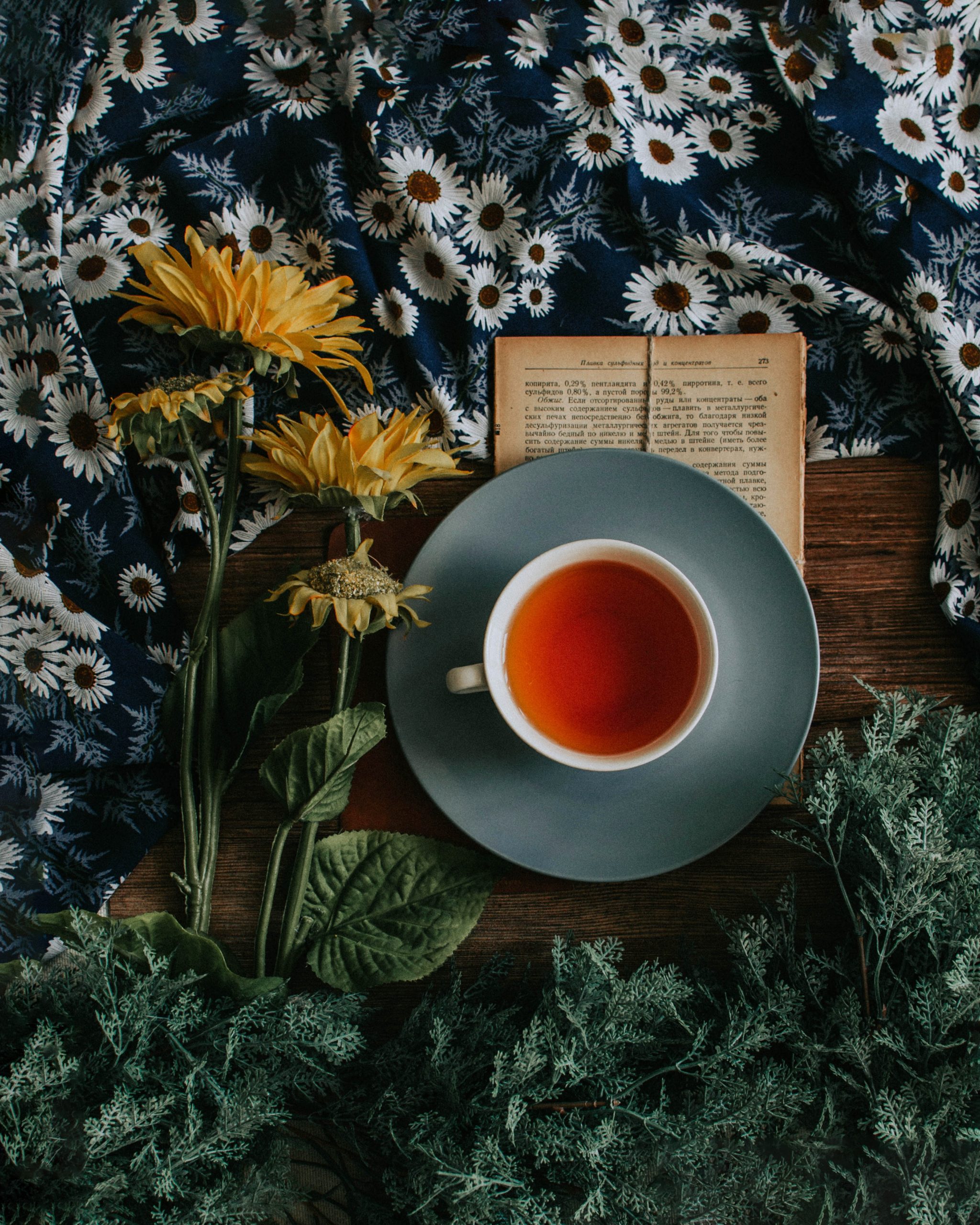 bird's eye view of a cup of tea with a flower and a book beside it