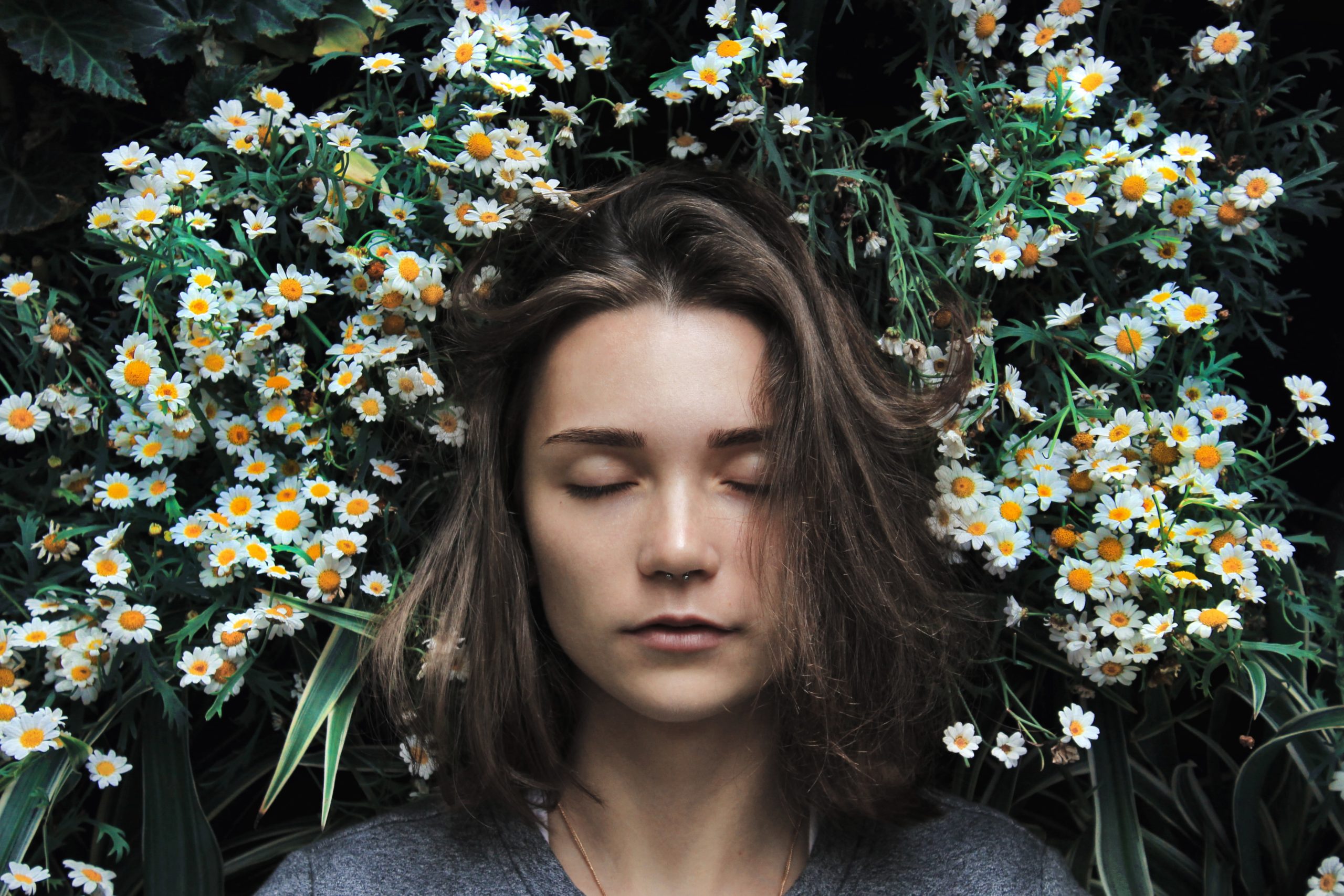 94: Mastering Your Mindset and Loving Your Body with Kaitlin Kreczmer woman with her eyes closes against a backdrop of white and yellow wildflowers