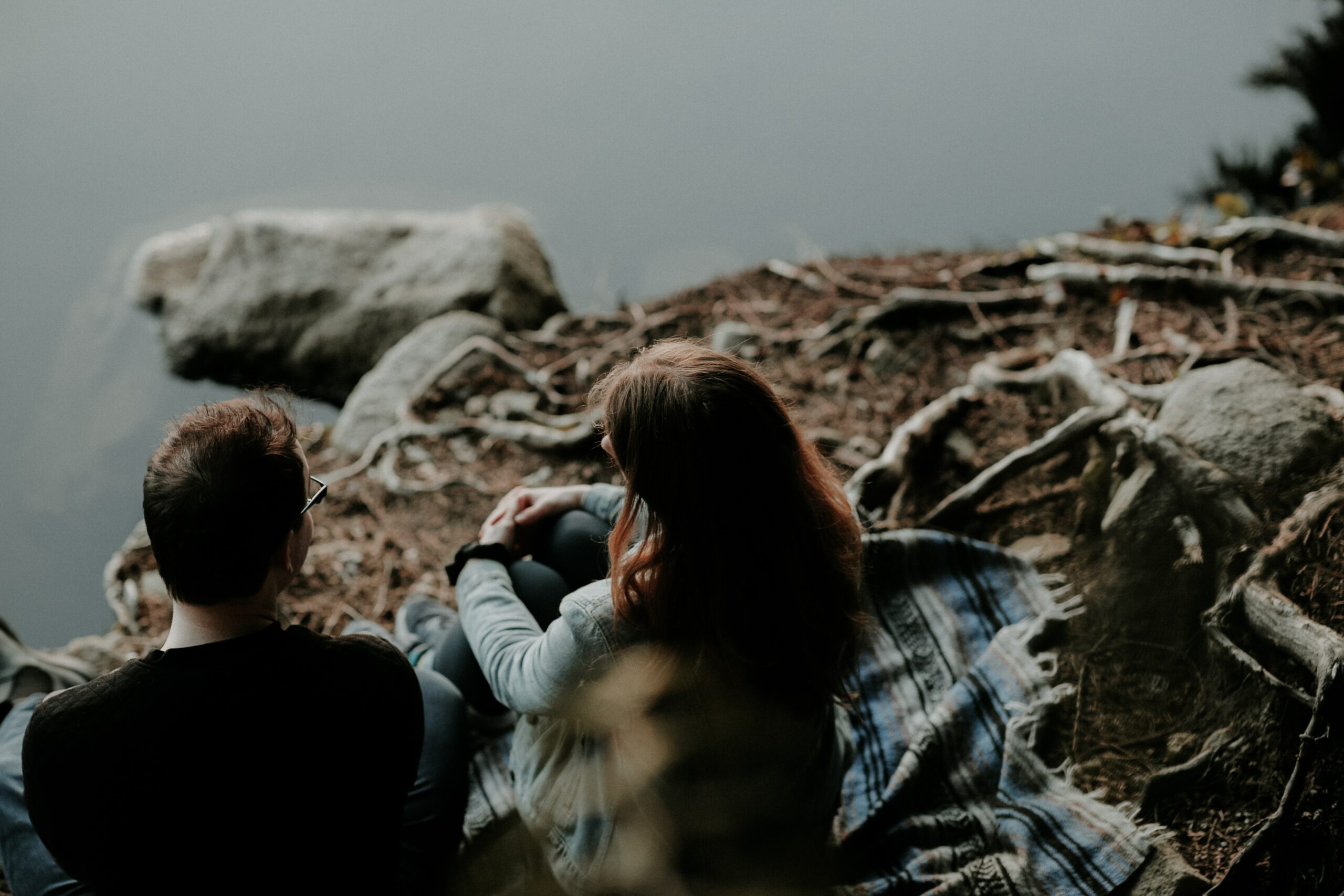man and woman sitting beside a body of water