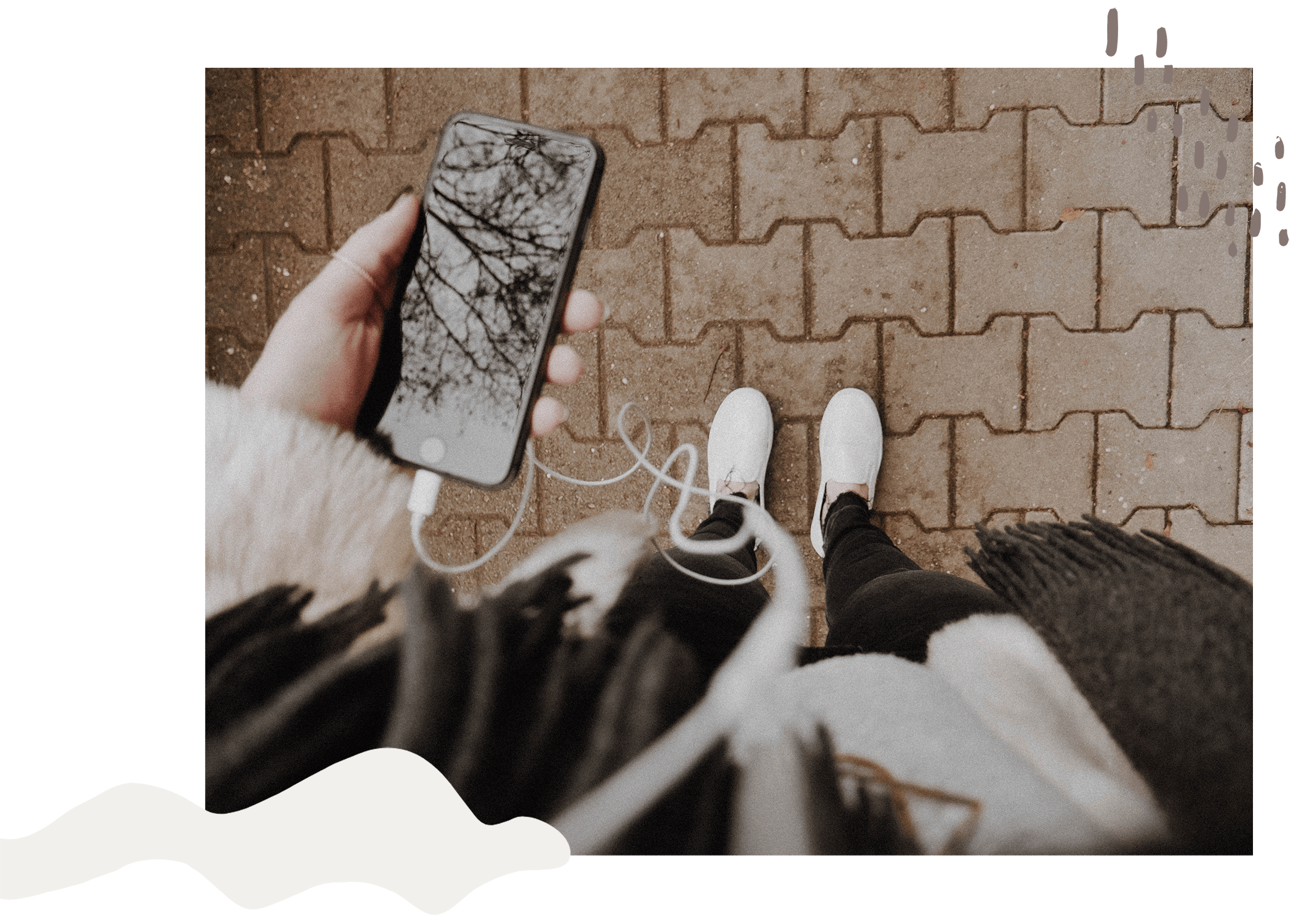 a woman holding a phone with headphones looking down at her shoes