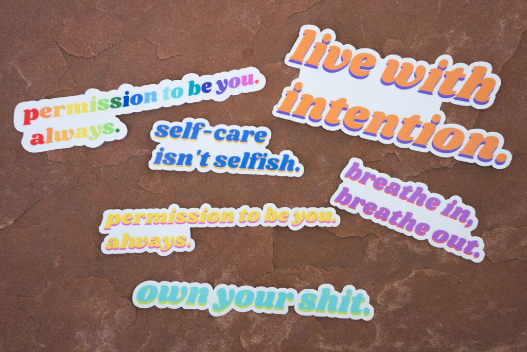 Spotlighting our Sticker Collection! Six stickers on a concrete surface