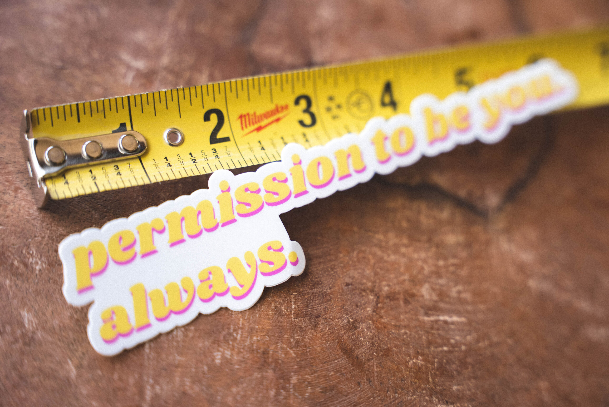 "Permission to be you. Always." Sticker Sticker that says "permission to be you. always." and a tape measure on a table
