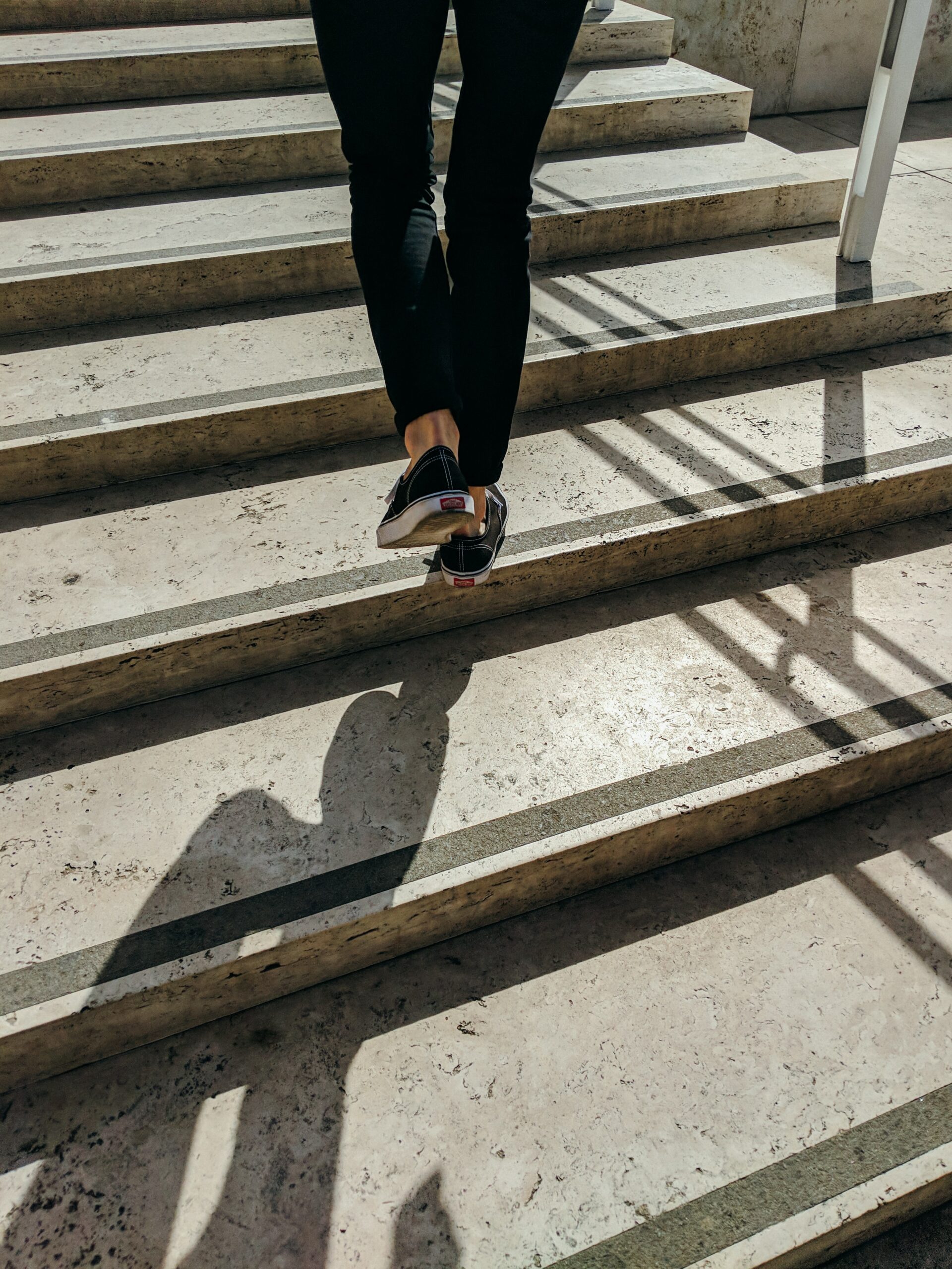 Little Steps Towards 2022 legs walking up a series of steps in shadows