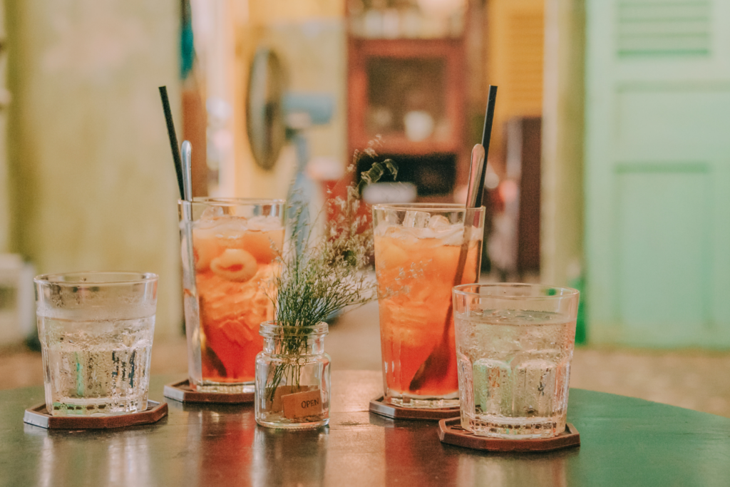four glasses filled with beverages on a black table