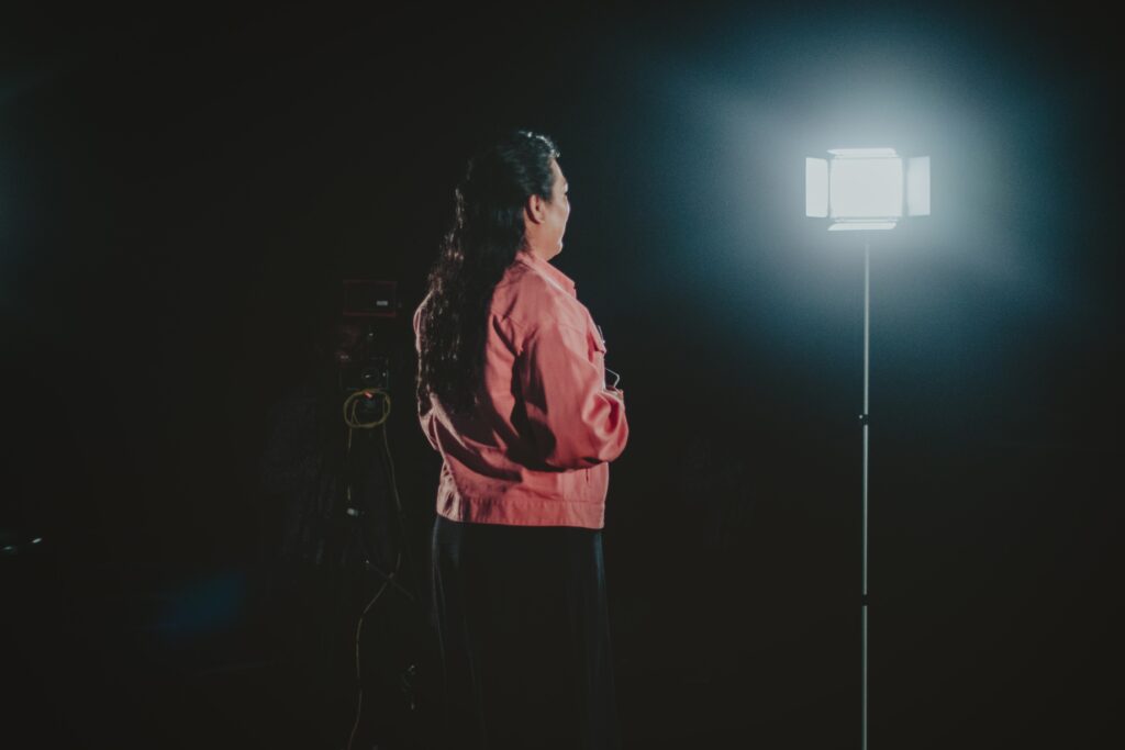 a woman in a pink shirt standing on a stage with lights on her