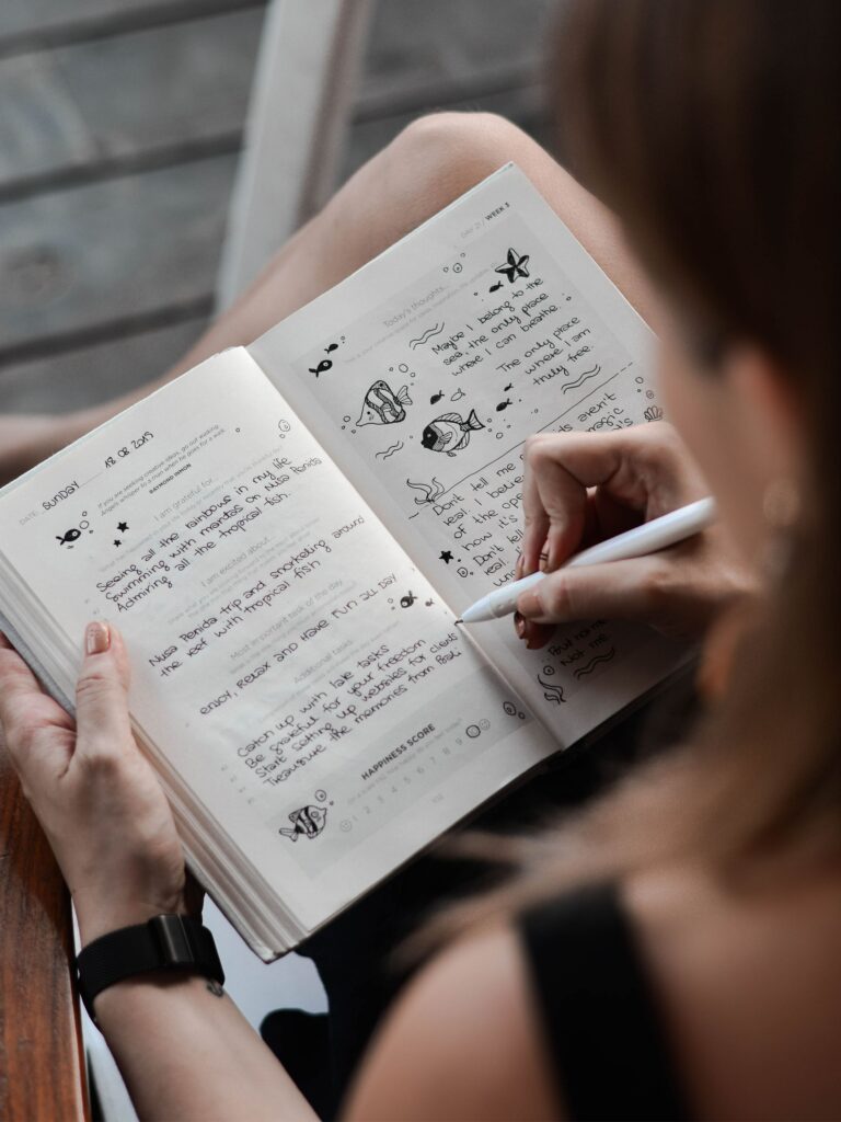 a woman journaling in a notebook with black ink