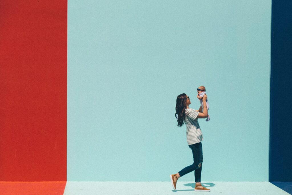 a long haired woman holding a baby up in front of her playfully