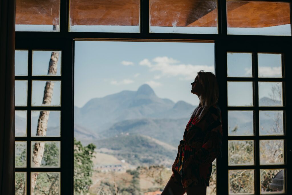 Even Life Coaches Get Insecure From Time to Time Silhouette of a woman leaning against a door frame in front of a mountainscape