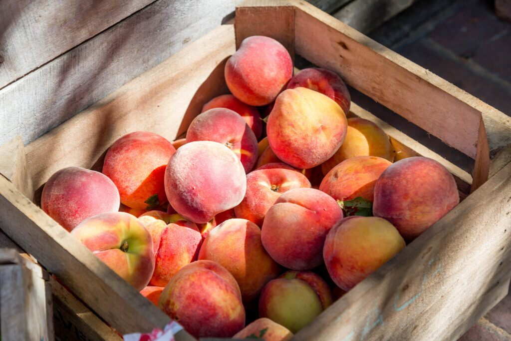 a wooden basket of peaches sitting in the sun