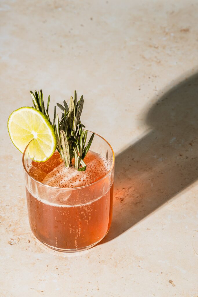 close up of a pink drink with a lime on a white concrete surface