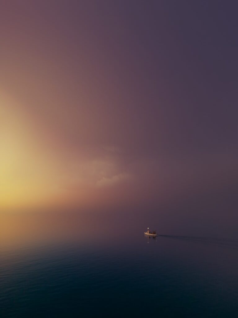 a lone boat in the middle of a black sea with purple and yellow sky