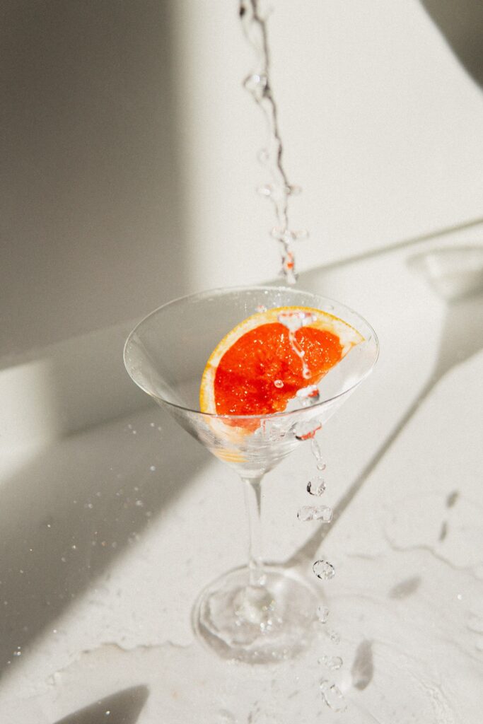 My Comfort Un-Drink close up of a clear martini glass with clear liquid and an orange slice
