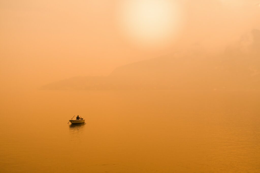 How to Meditate: A 2022 Guide for Beginners a wide photo of a single boat on still waters at sunset